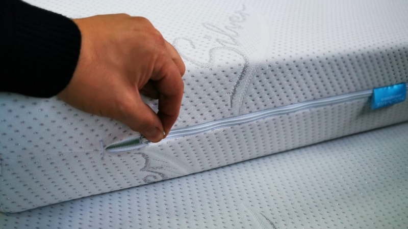 Osoba otkopčava rajsferšlus na dušeku sa belom navlakom