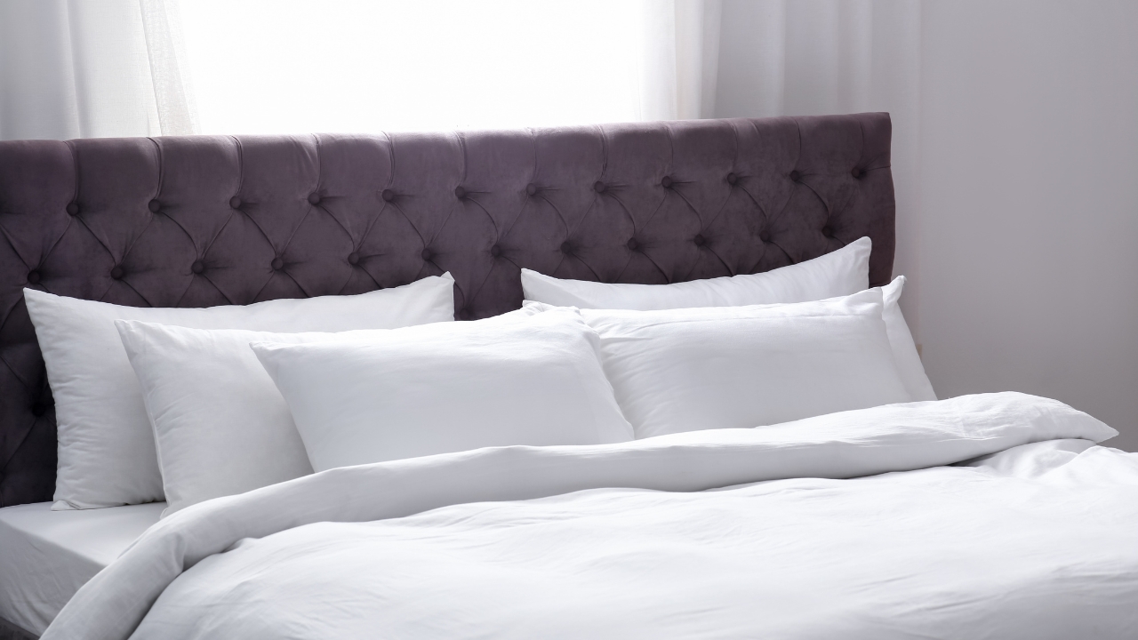 Krevet sa tapaciranim uzglavljem i belom posteljinom koji izgleda uredno i osveženo